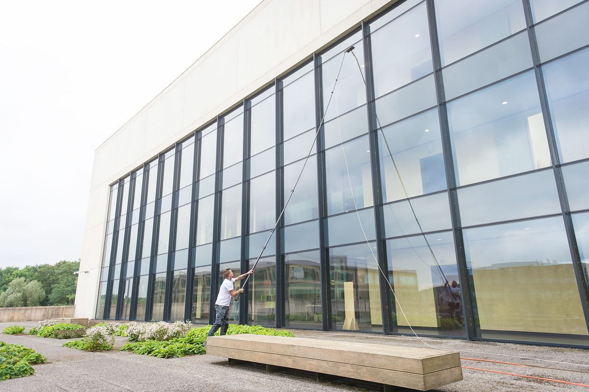 Ramenwasser wast de glazen gevel van een bedrijfspand met een telescoopsteel